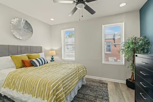 Furnished bedroom with a ceiling fan and yellow bedding